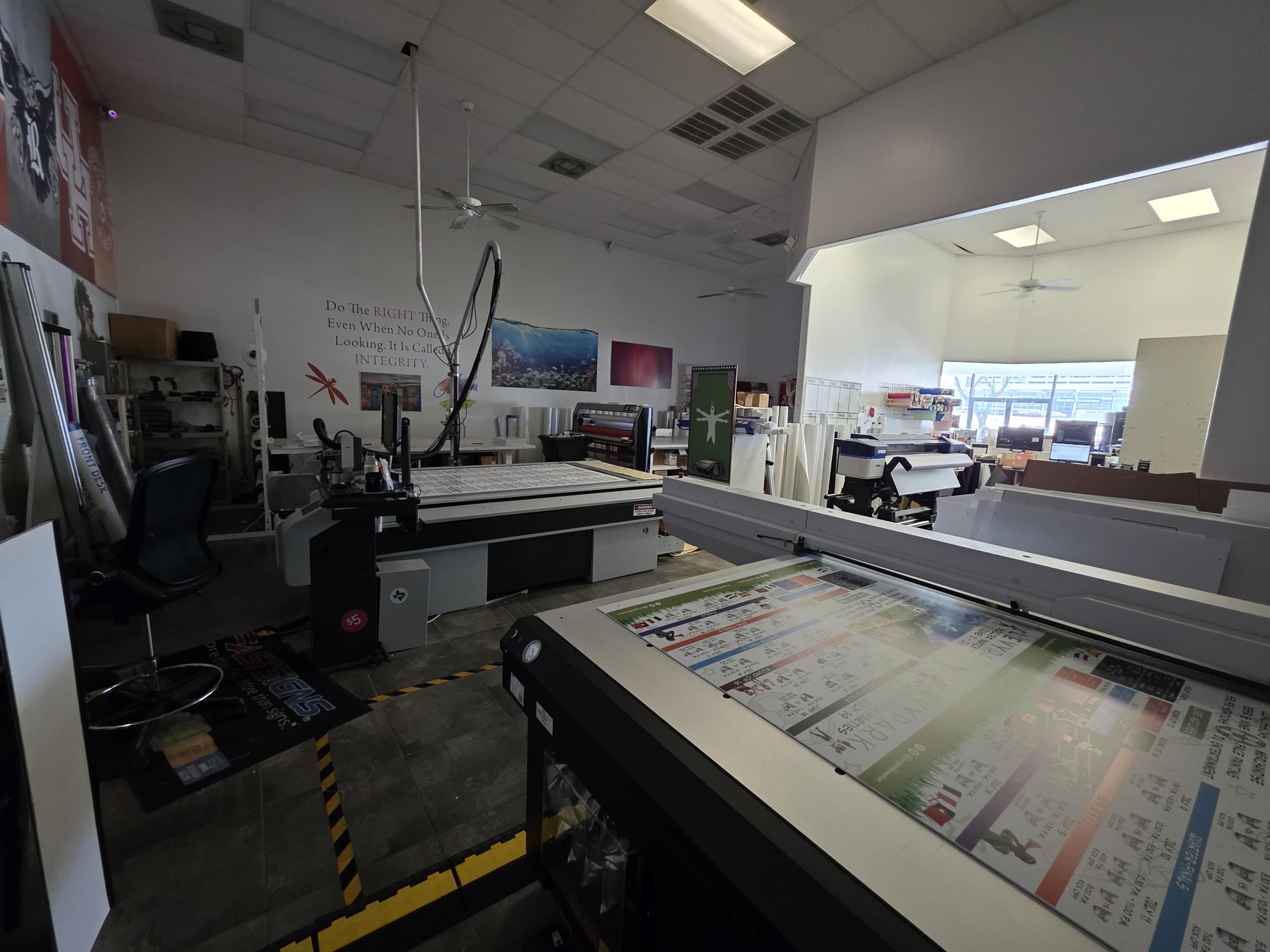 The FASTSIGNS production floor in Spring, TX — flatbed cutter and large-format printer